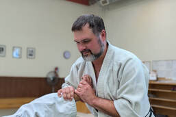 Assistant instructor Jeremy Wojcik holds a students wrist in a nikkyo lock.